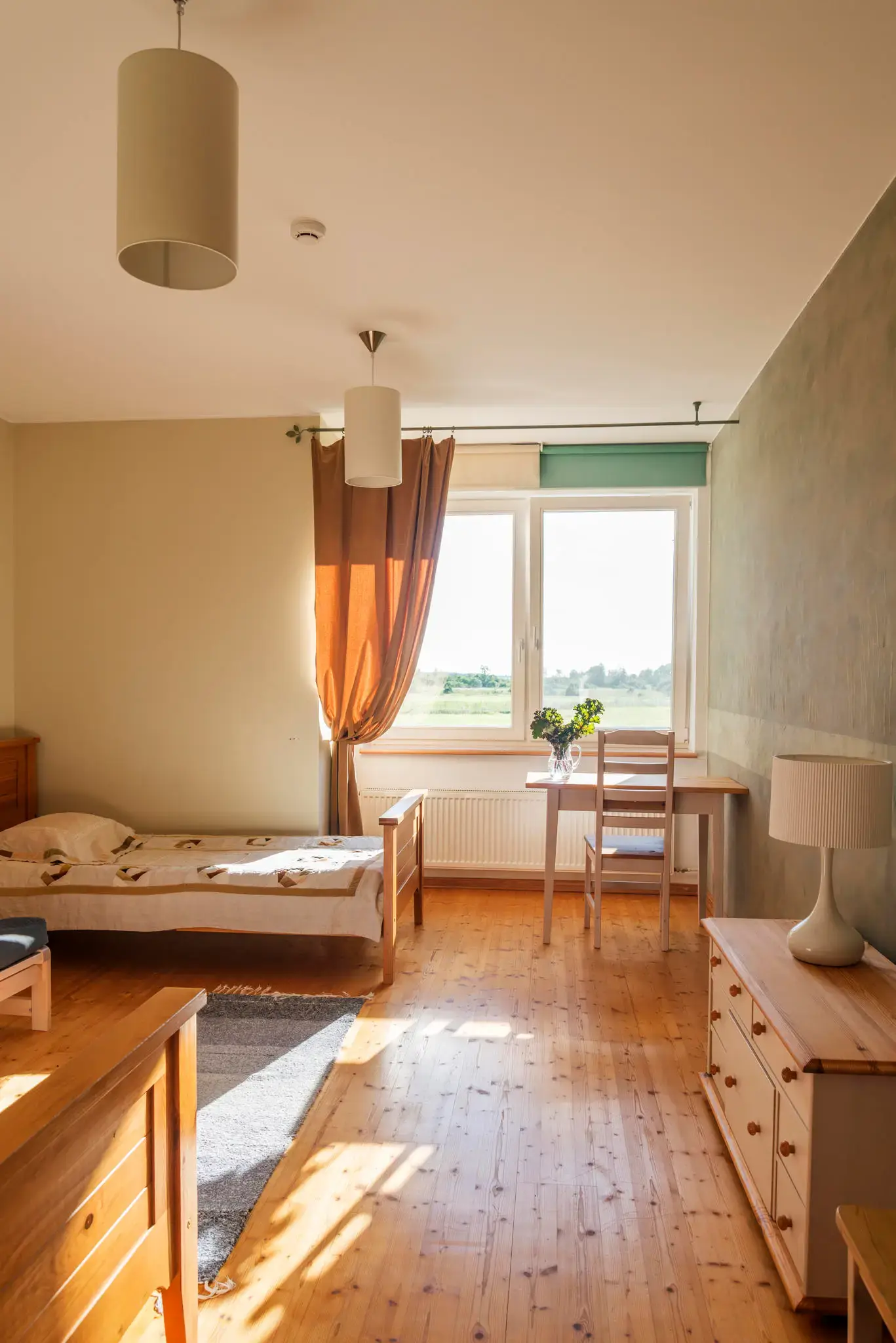 Sunlit room with a single bed, desk and view over the fields