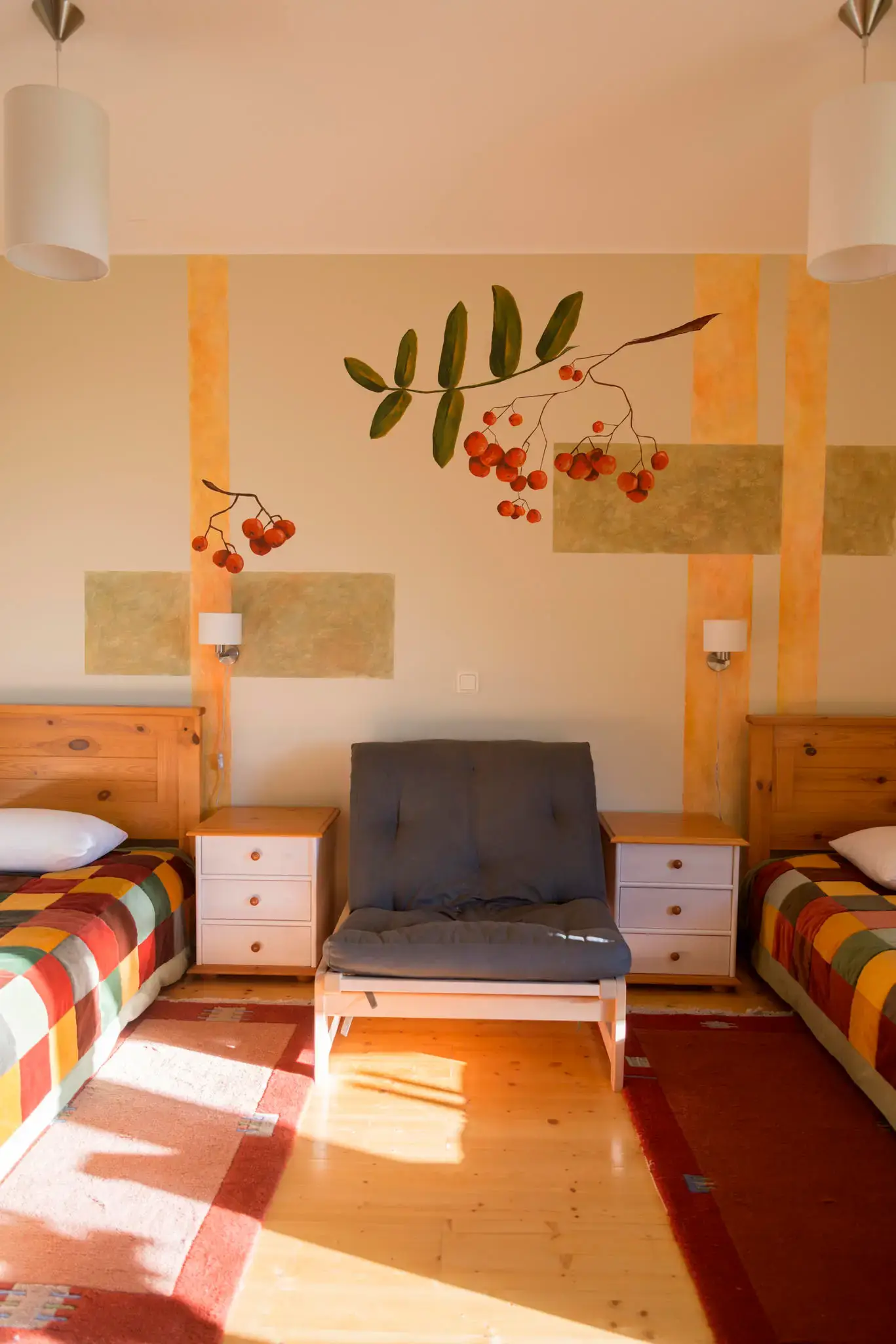 Twin beds either side of a painted rowan branch mural