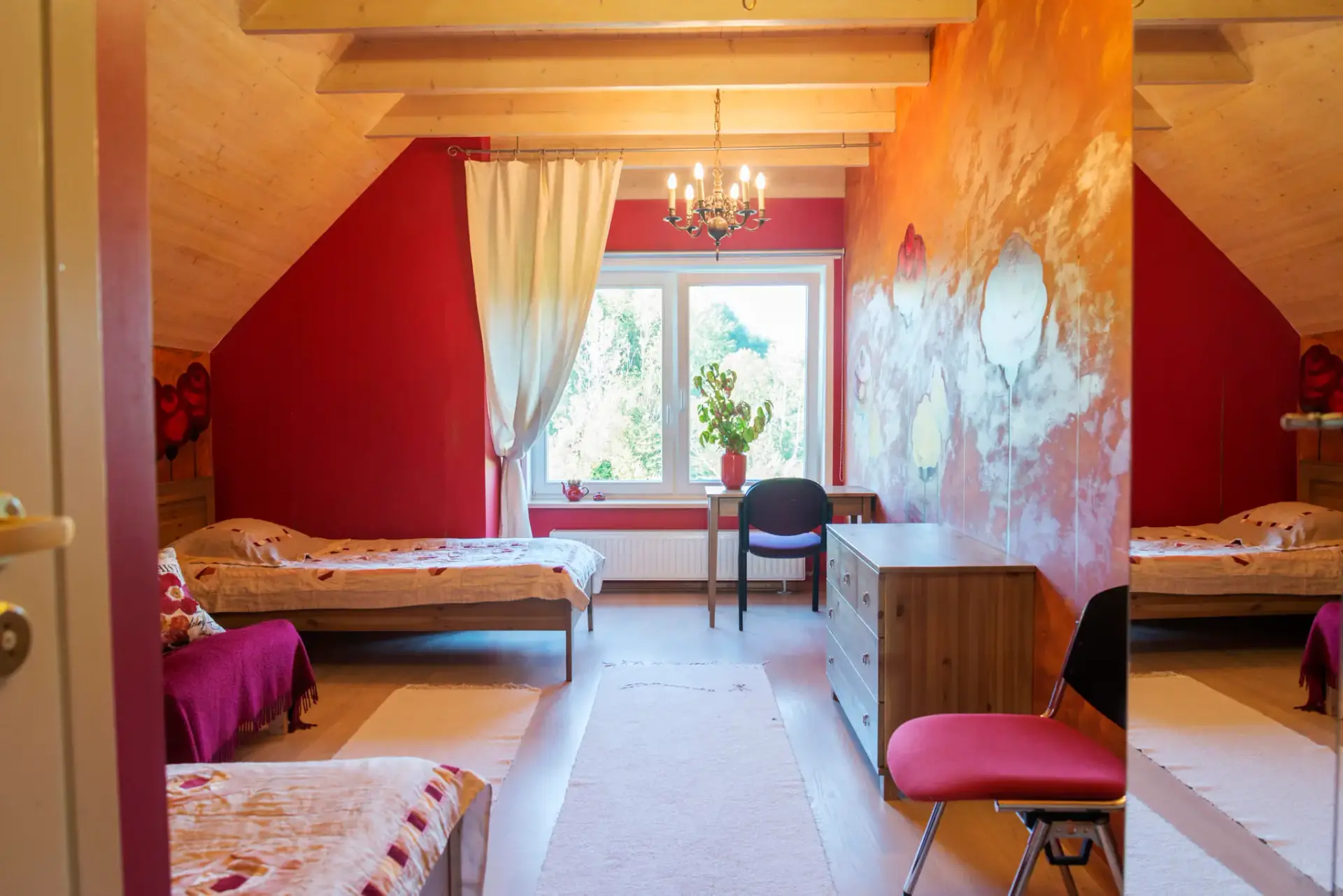 Red room with three single beds under a beamed ceiling