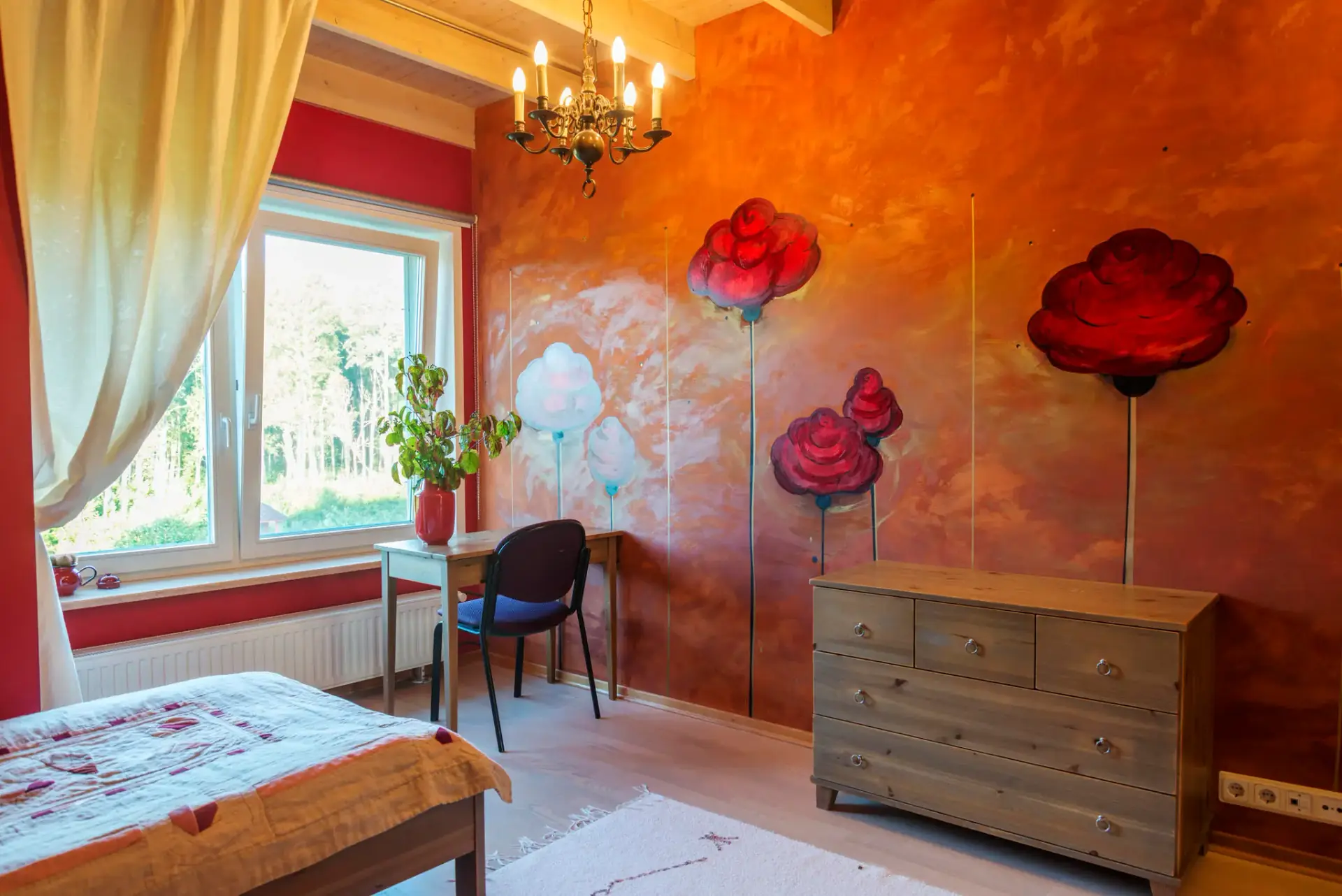 Room with painted red roses on the wall, bed and writing desk